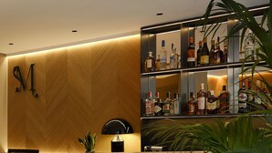 Eine Bar mit Holzwand, einem Regal voller Flaschen und zwei Barhocker.
