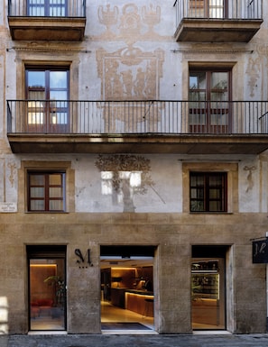 Un edificio con balcón, varias ventanas y entrada a una tienda.
