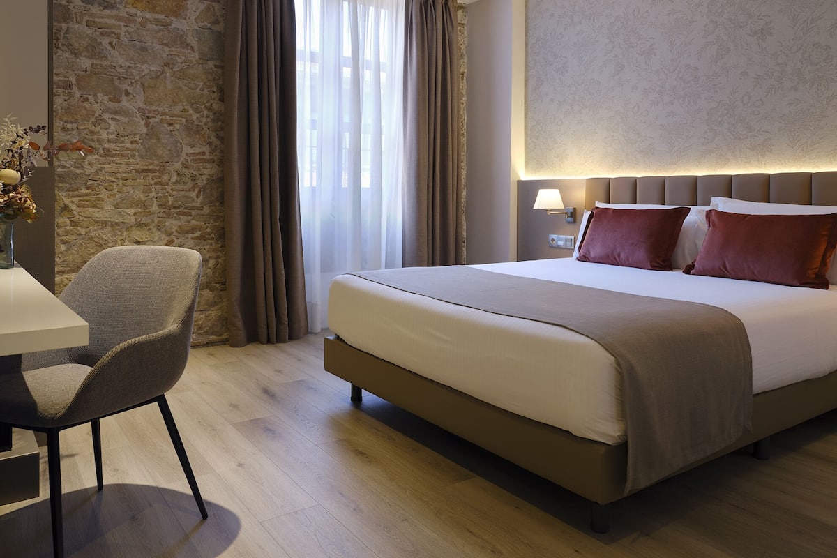 Una habitación de hotel con una cama grande, un escritorio y una silla.