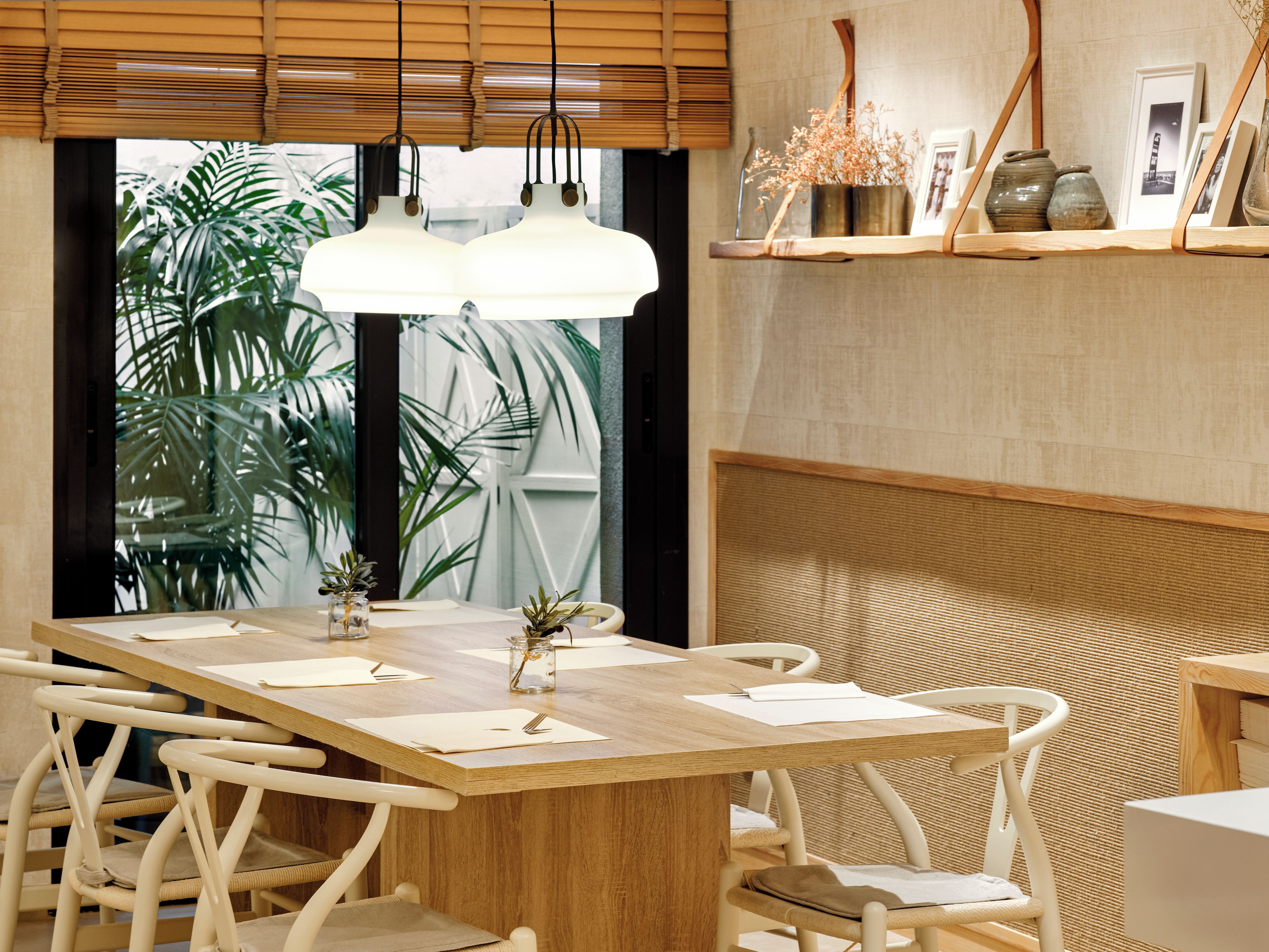 Un comedor con una mesa de madera, sillas blancas y lámparas colgantes.