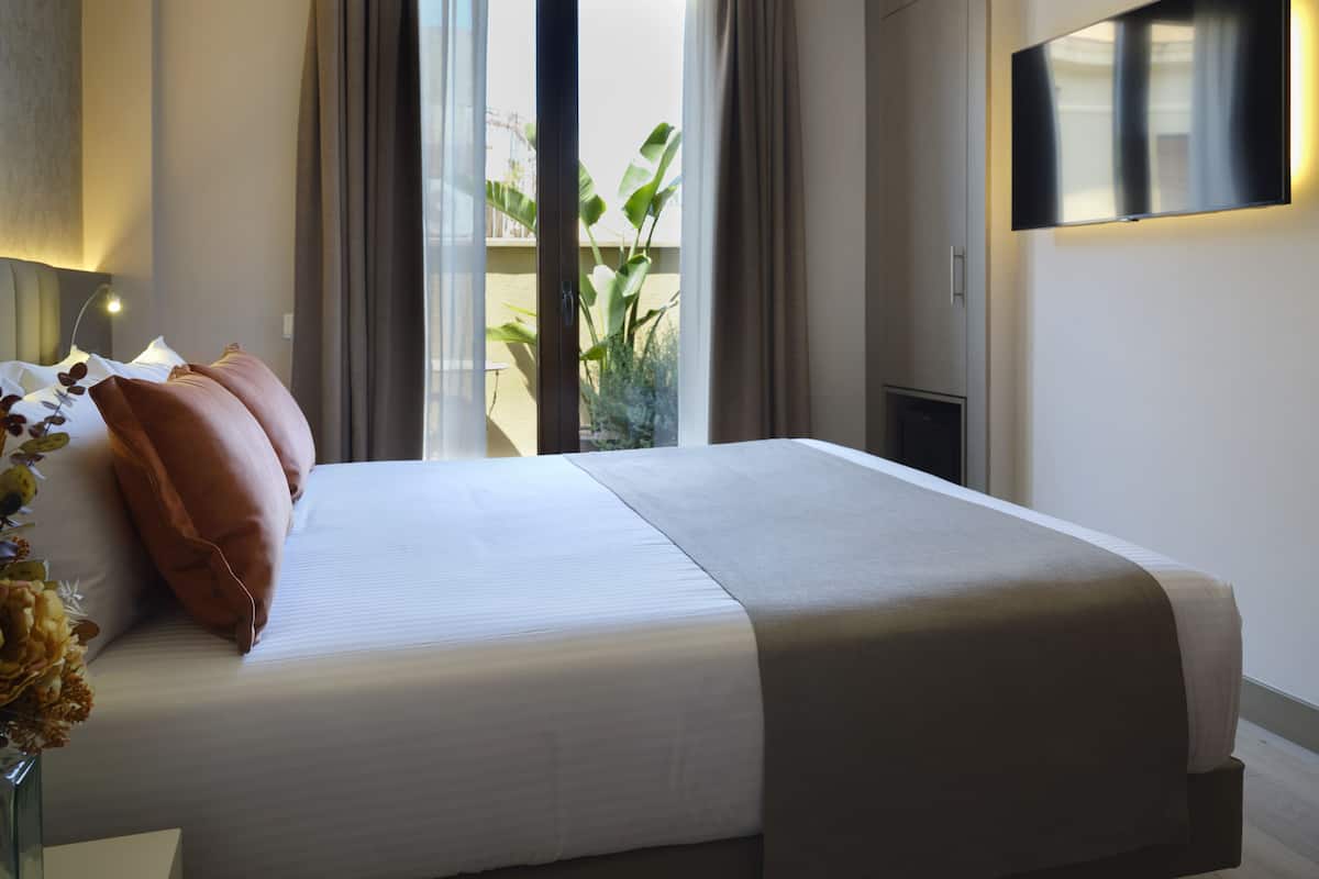 Habitación de hotel con cama, televisión y vistas al exterior.