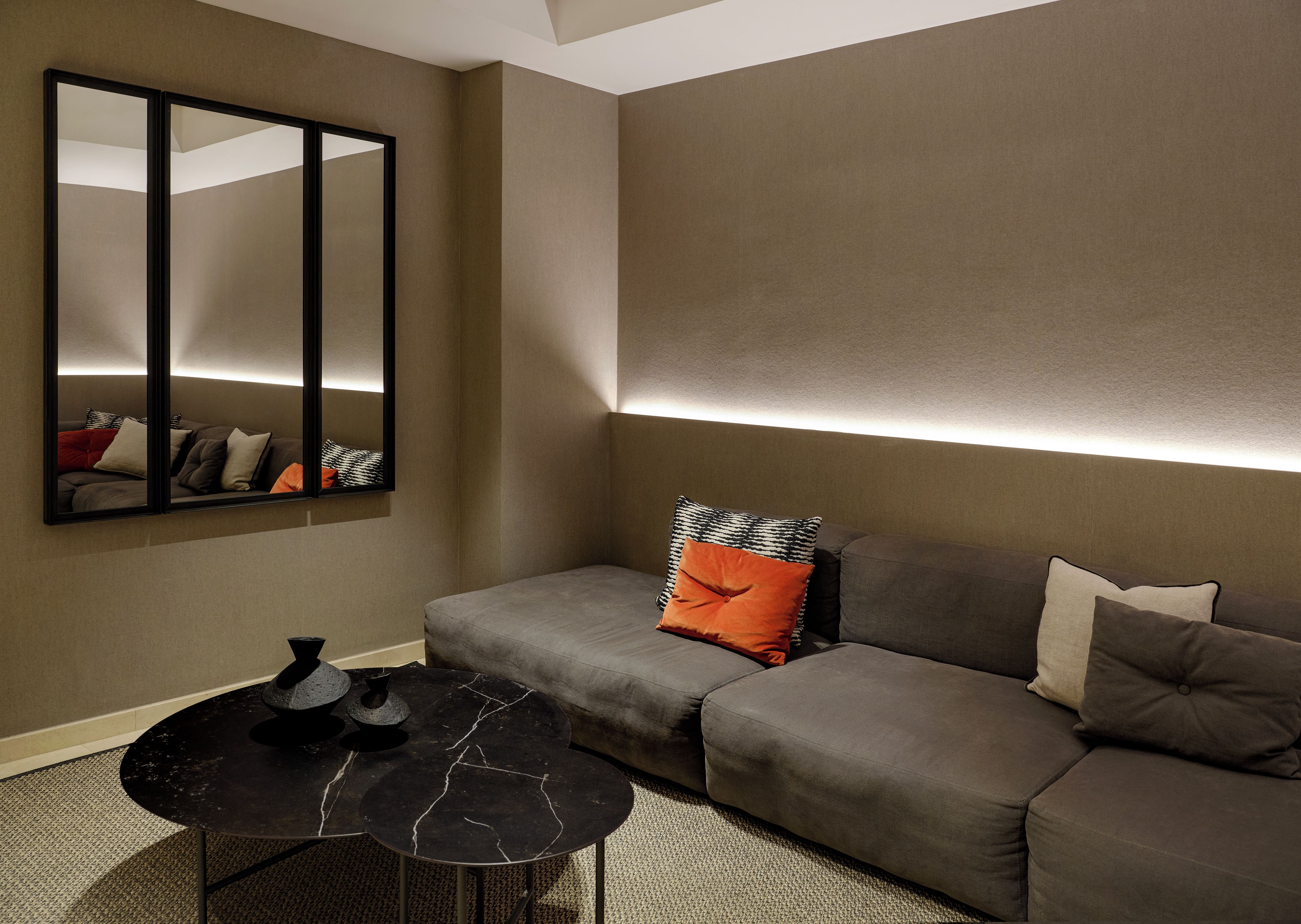 A modern living room with a sofa, a coffee table, and a wall-mounted mirror.