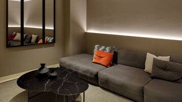 A modern living room with a sofa, a coffee table, and a wall-mounted mirror.