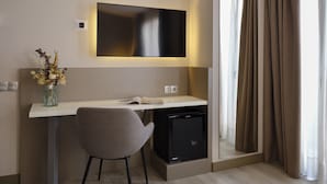 A modern hotel room with a desk, chair, flat-screen TV, and a small refrigerator. - Musik Boutique Hotel - Adults Only (Barcelona)