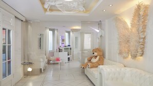 A spacious living room with a large white sofa, a teddy bear, and decorative wall art. - Vice Versa (Paris)