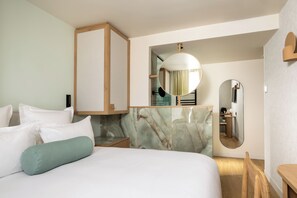Ein Hotelzimmer mit einem Bett, einem Holzschrank, einem Spiegel und einer Marmorwand.