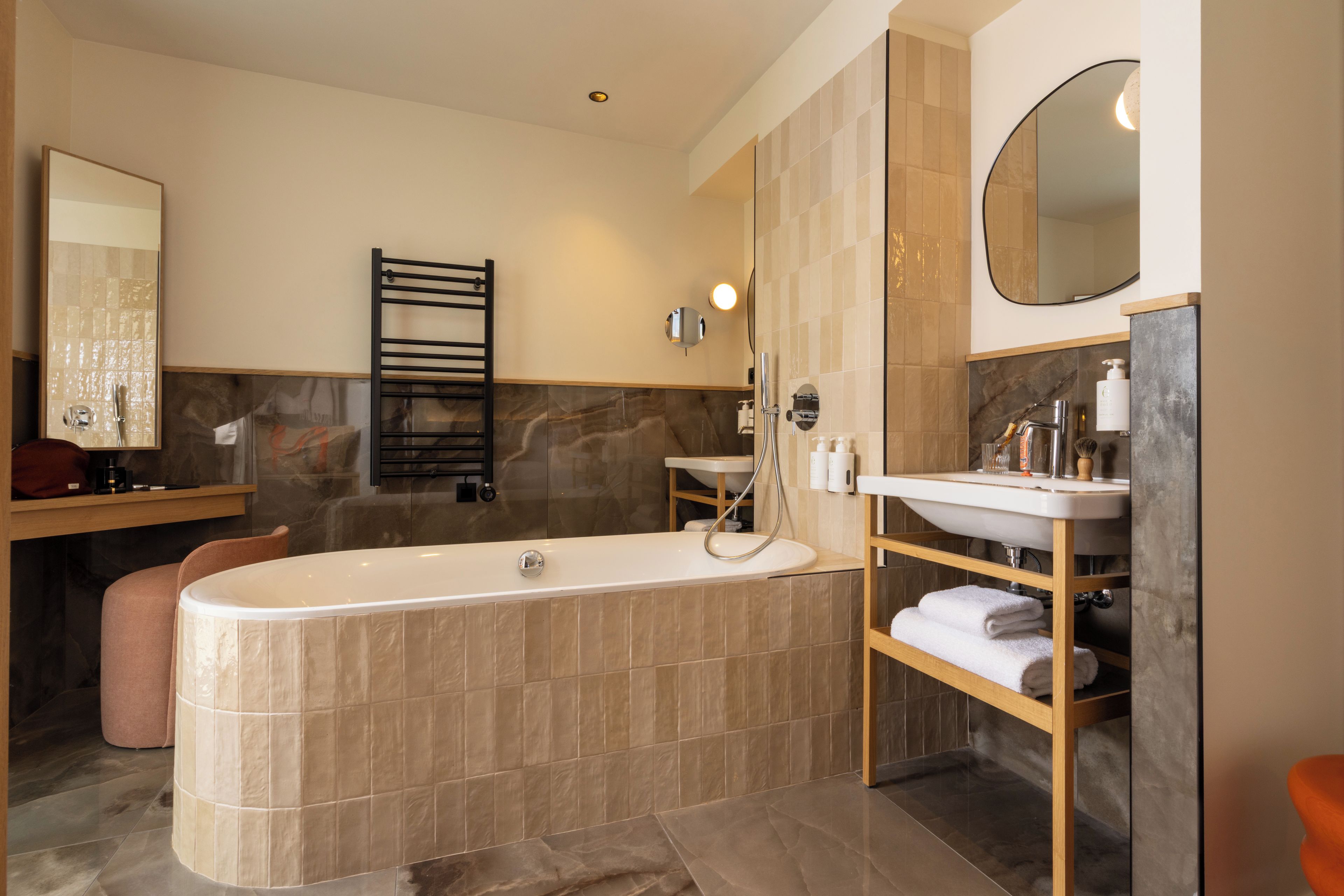 A modern bathroom with a freestanding bathtub, a vanity with a mirror, and a towel rack.