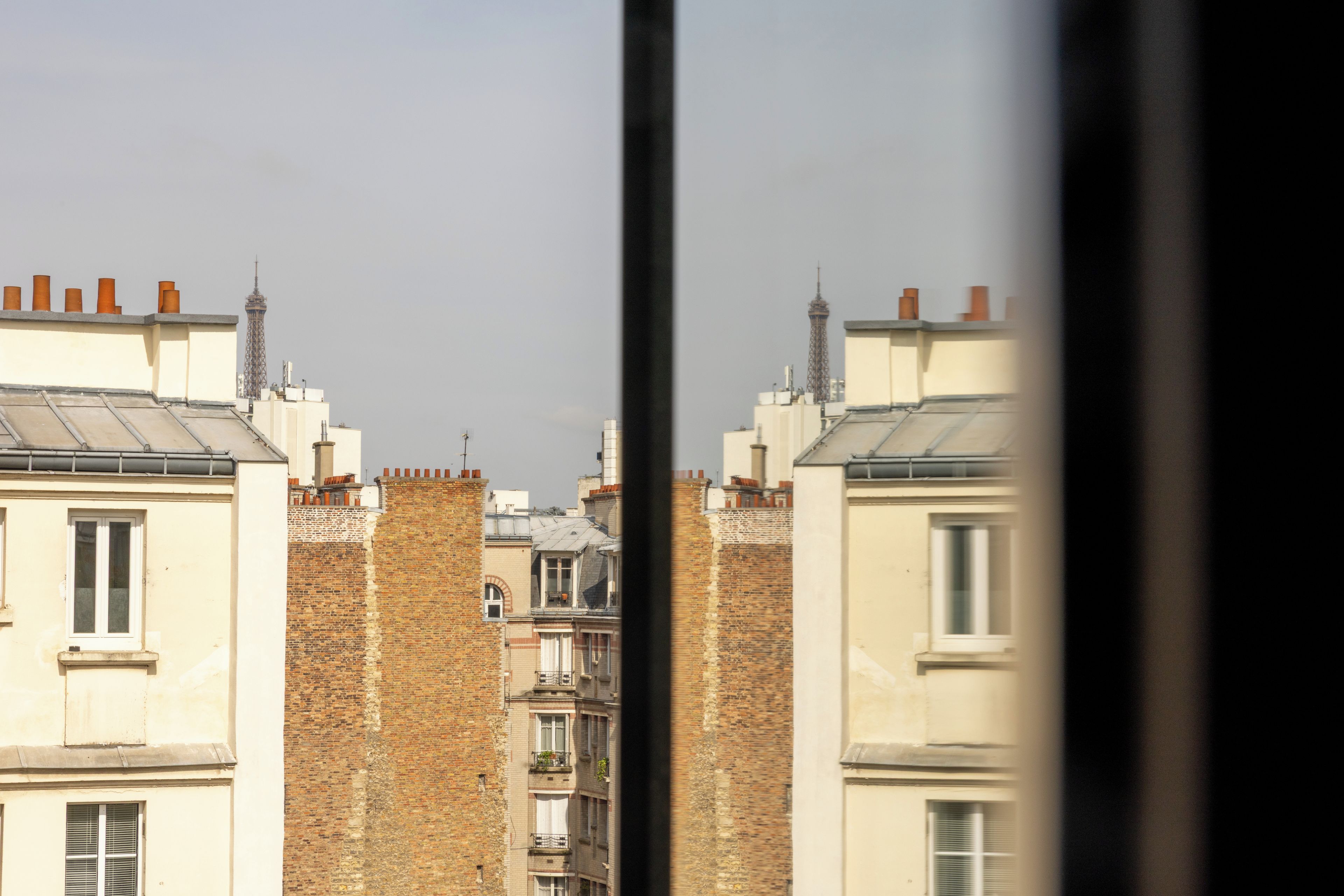 A row of buildings with brick facades and flat roofs, viewed through a window frame.