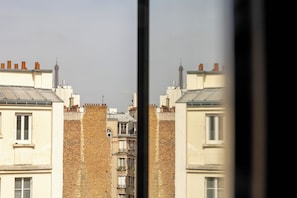 A row of buildings with brick facades and flat roofs, viewed through a window frame. - Vice Versa (Paris)