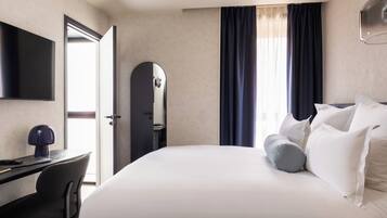 Ein Hotelzimmer mit einem Bett, einem Schreibtisch mit Stuhl, einem Fernseher und einer Tür.