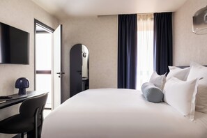 A hotel room with a bed, a desk with a chair, a television, and a door. - Vice Versa (Paris)