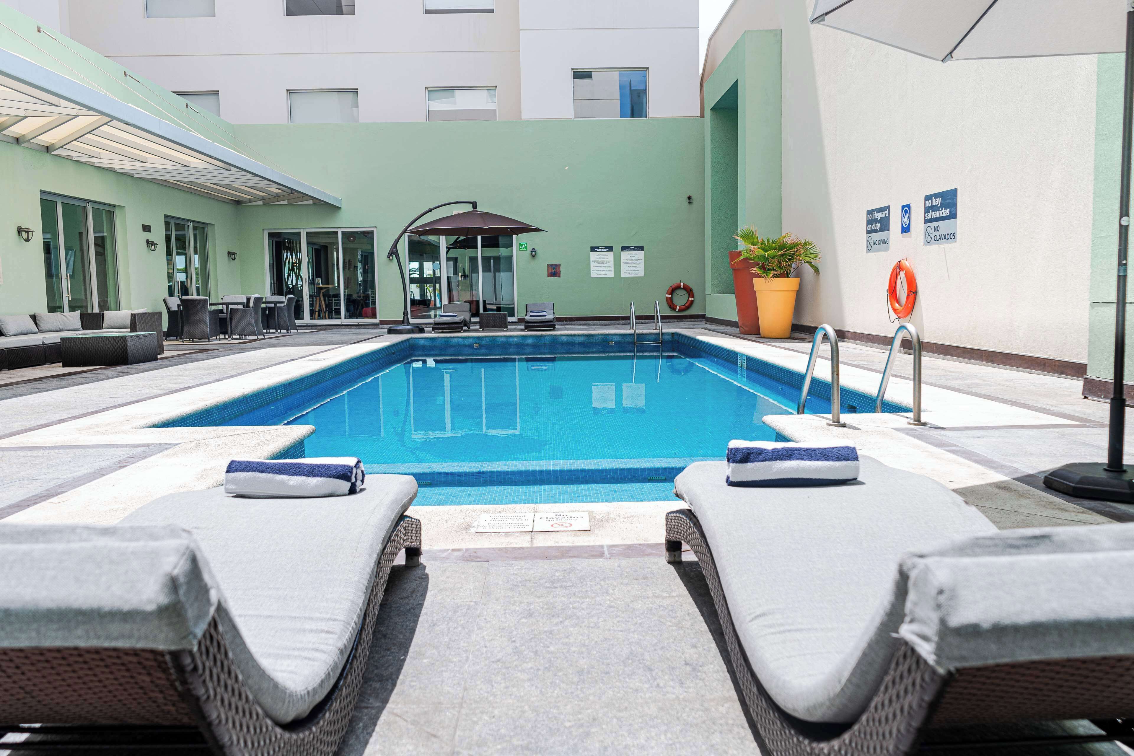A pool area with lounge chairs and a covered seating area.
