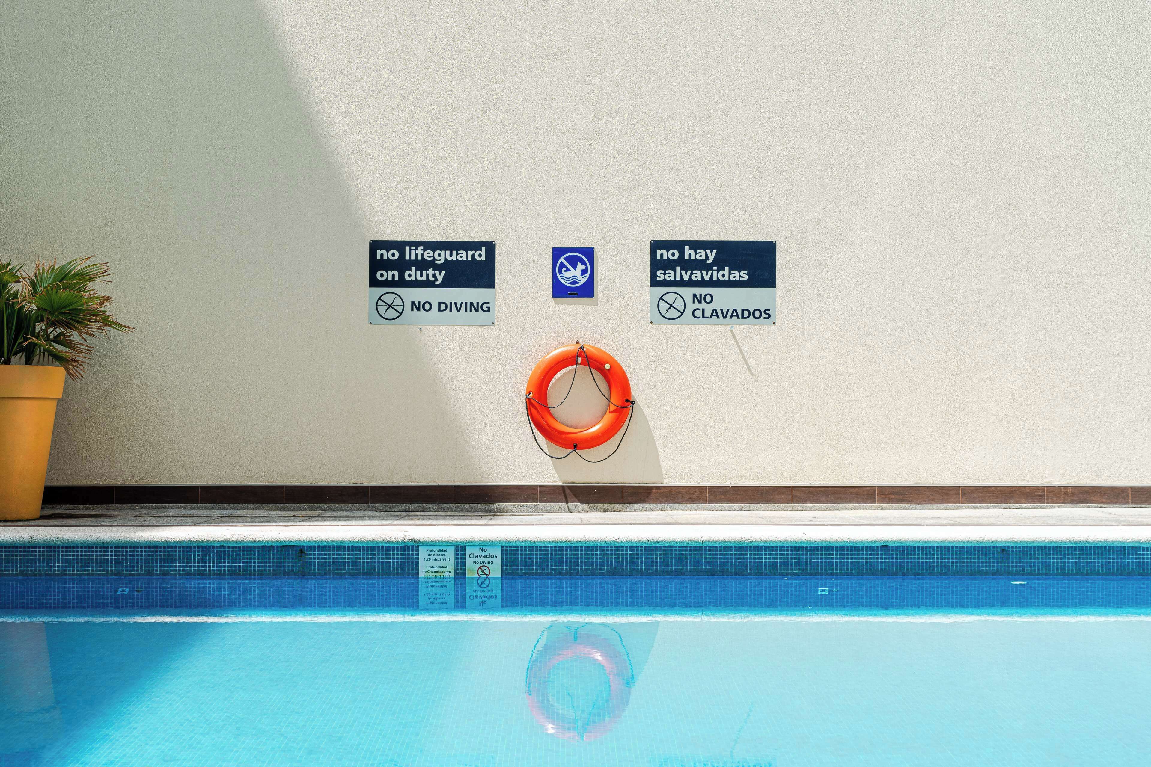 A swimming pool with safety signs indicating no diving and no swimming.