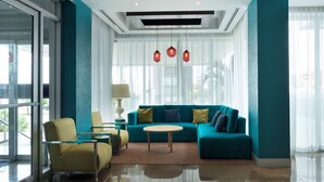 A modern living room with a teal sofa, a round coffee table, and a patterned armchair.