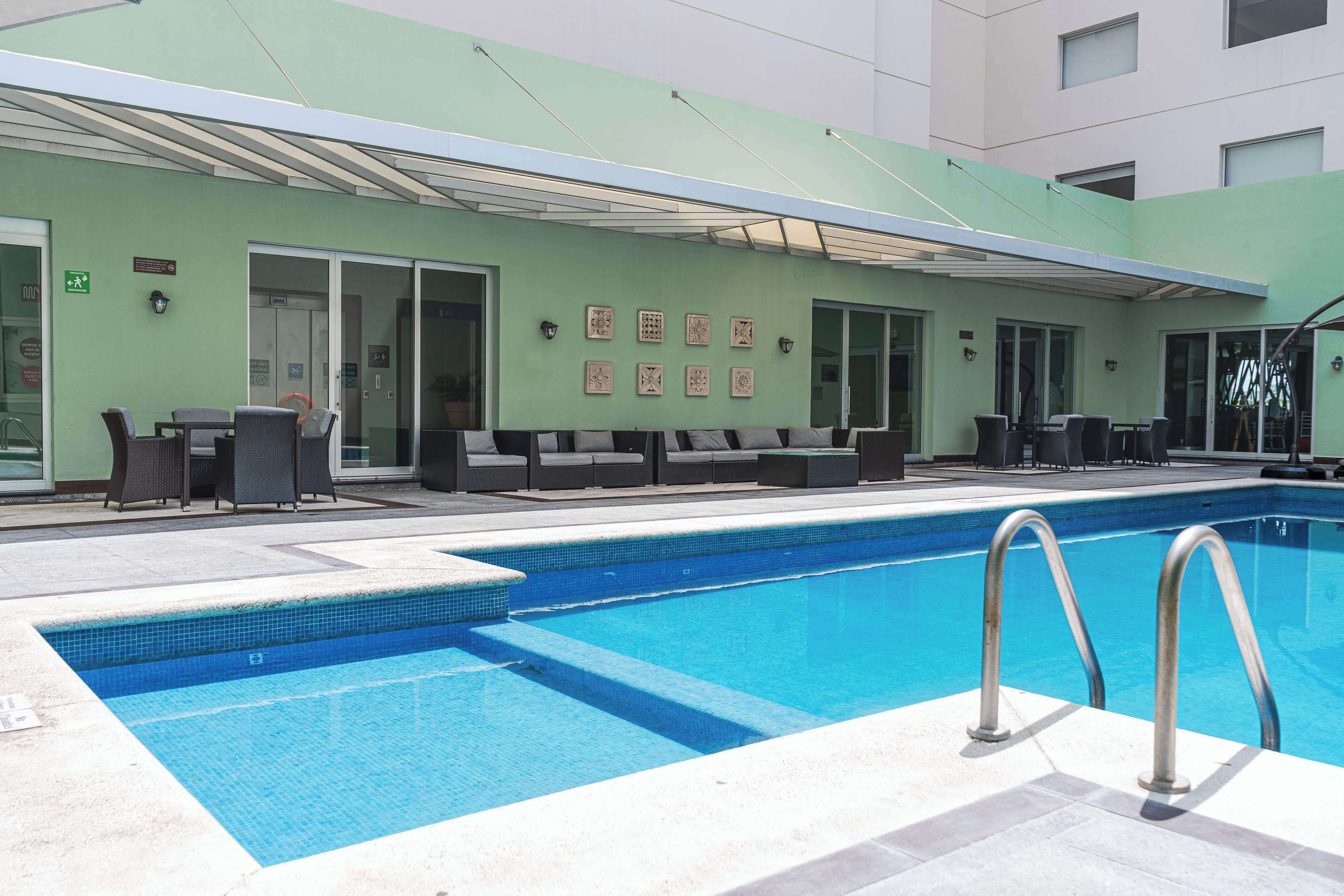 A swimming pool with lounge chairs and a covered seating area.