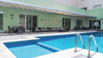 A swimming pool with lounge chairs and a covered seating area.