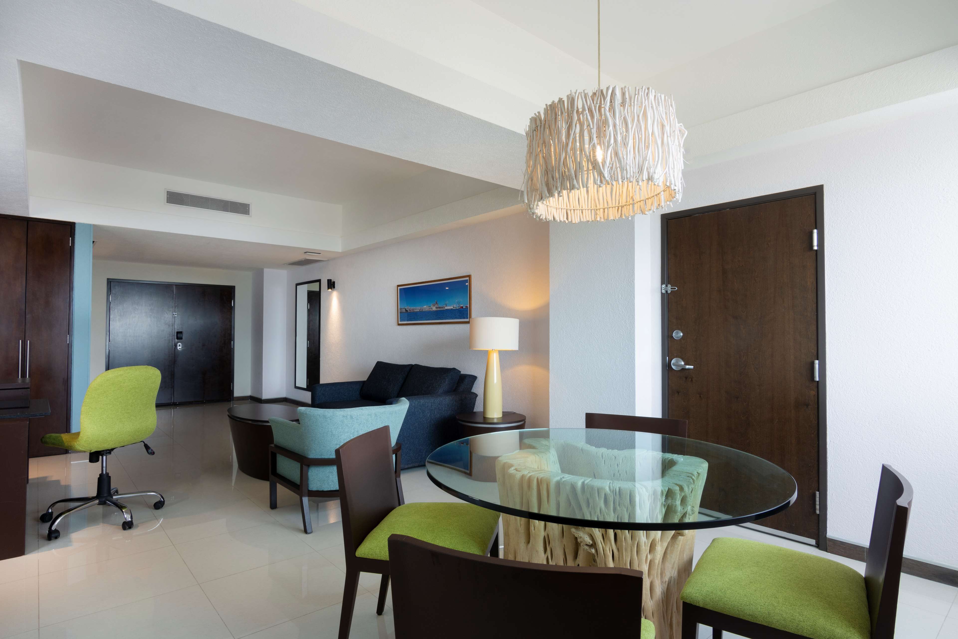 A modern living room with a glass dining table, a sofa, and a chair.