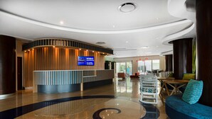 A modern lobby with a reception desk, seating area, and a curved ceiling design.