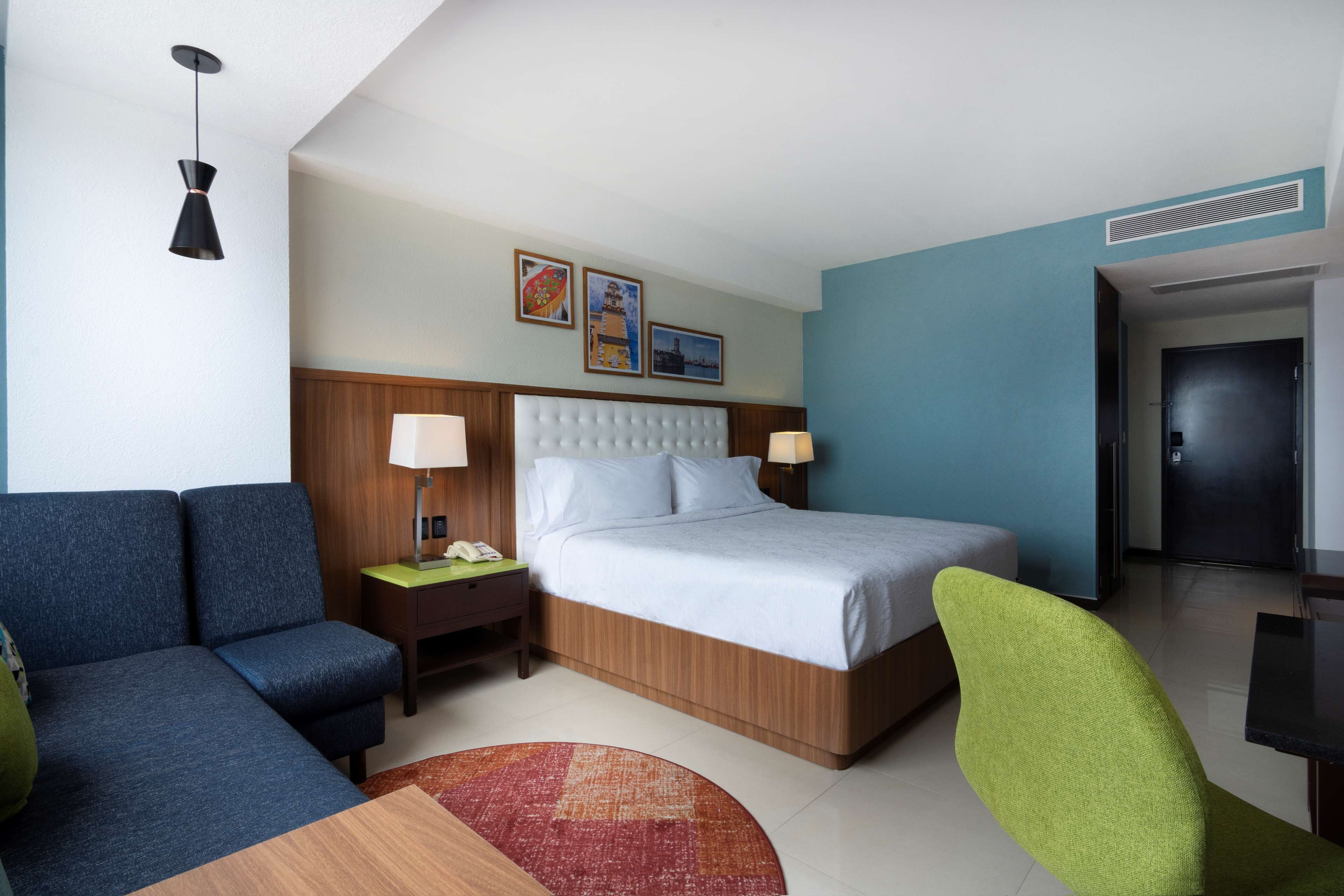 A hotel room with a bed, a sofa, a desk, and a chair.