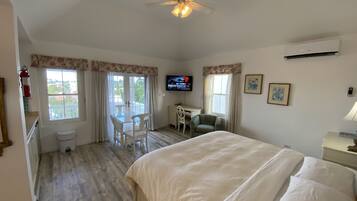A bedroom with a large bed, a desk, a chair, and a ceiling fan.