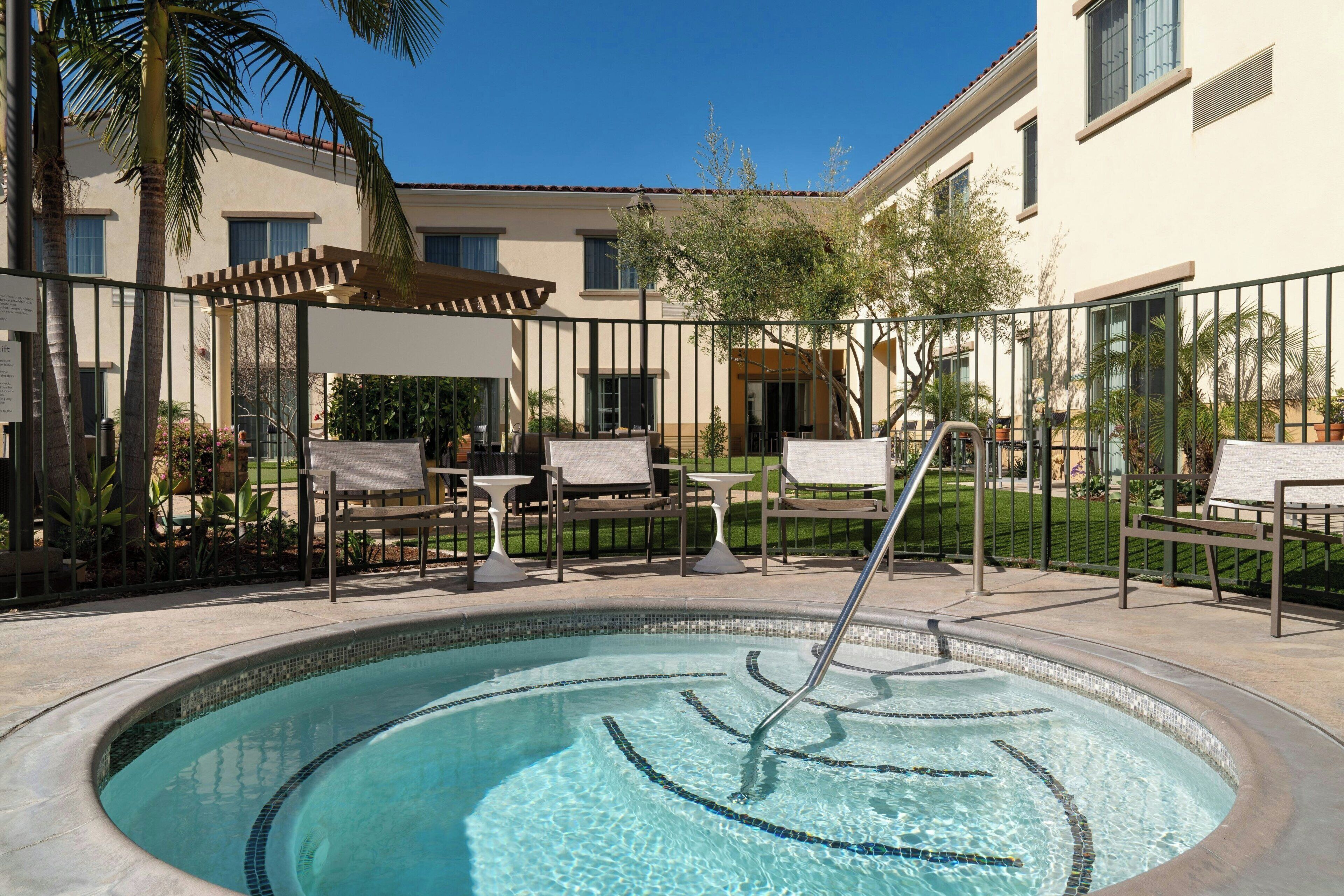 A swimming pool with a tiled edge, surrounded by lounge chairs and a pergola.