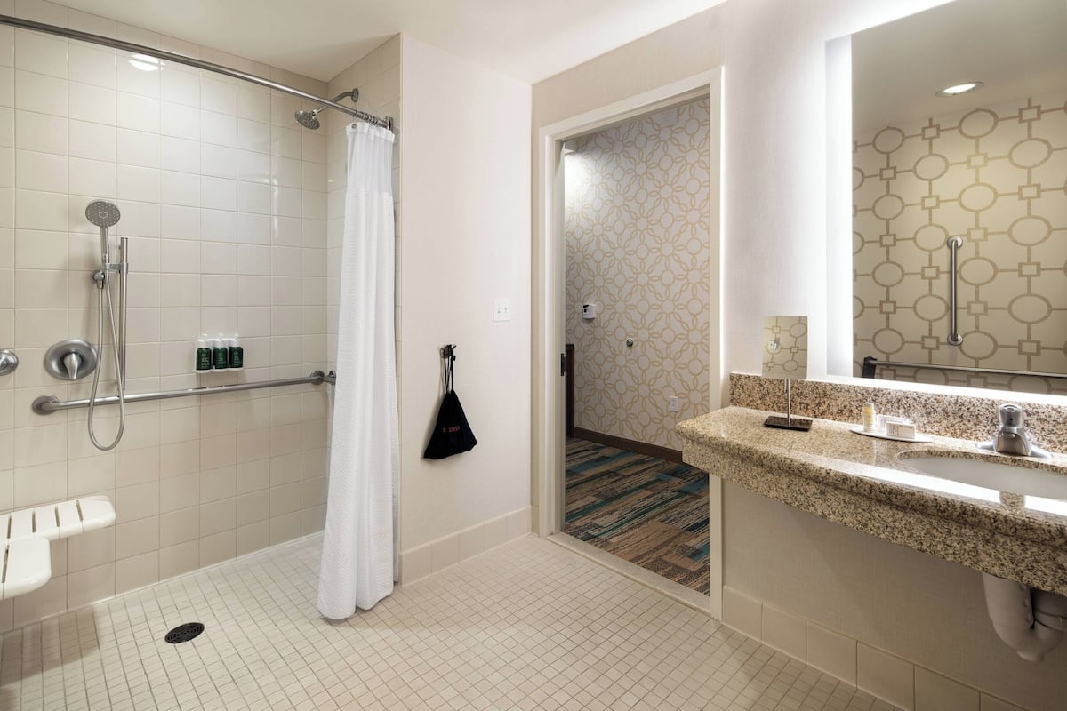 A modern bathroom with a walk-in shower, a toilet, and a sink with a granite countertop.
