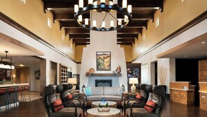 A spacious living area with a fireplace, comfortable seating, and a large chandelier. - Courtyard Santa Barbara Goleta (Goleta)