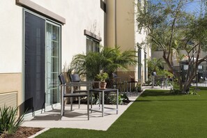 A patio area with outdoor furniture, a small garden, and a building facade.