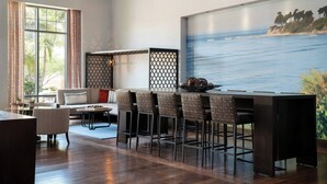 A modern living room with a wooden floor, a sofa, a coffee table, and a dining area with bar stools. - Courtyard Santa Barbara Goleta (Goleta)