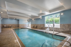 Piscina con carriles delimitados, una silla de salvavidas y una ventana con vistas a árboles.