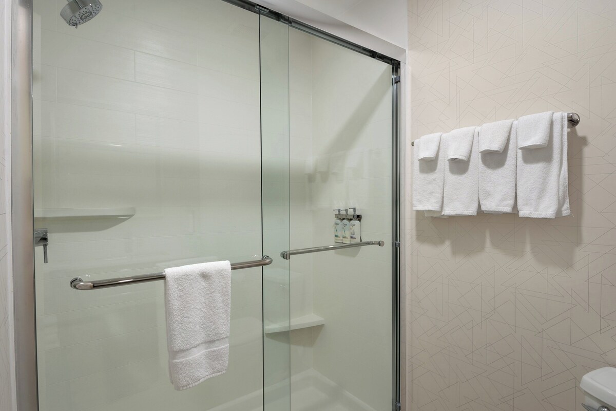 A glass-enclosed shower with a towel rack and a toilet visible in the corner.