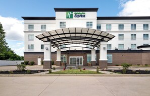 A Holiday Inn Express building with a covered entrance, brick facade, and a clear sky.