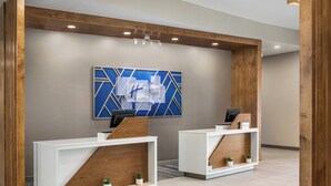 A reception area with two white reception desks, a blue and white geometric wall art, and a wooden accent wall. - Holiday Inn Express Richmond by IHG (Richmond)