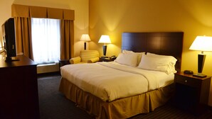 Una camera d'albergo con un letto grande, due abat-jour, una sedia e una scrivania con lampada.