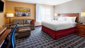 A hotel room with a bed, a sofa, a desk, and a TV. - TownePlace Suites Midland (Midland)