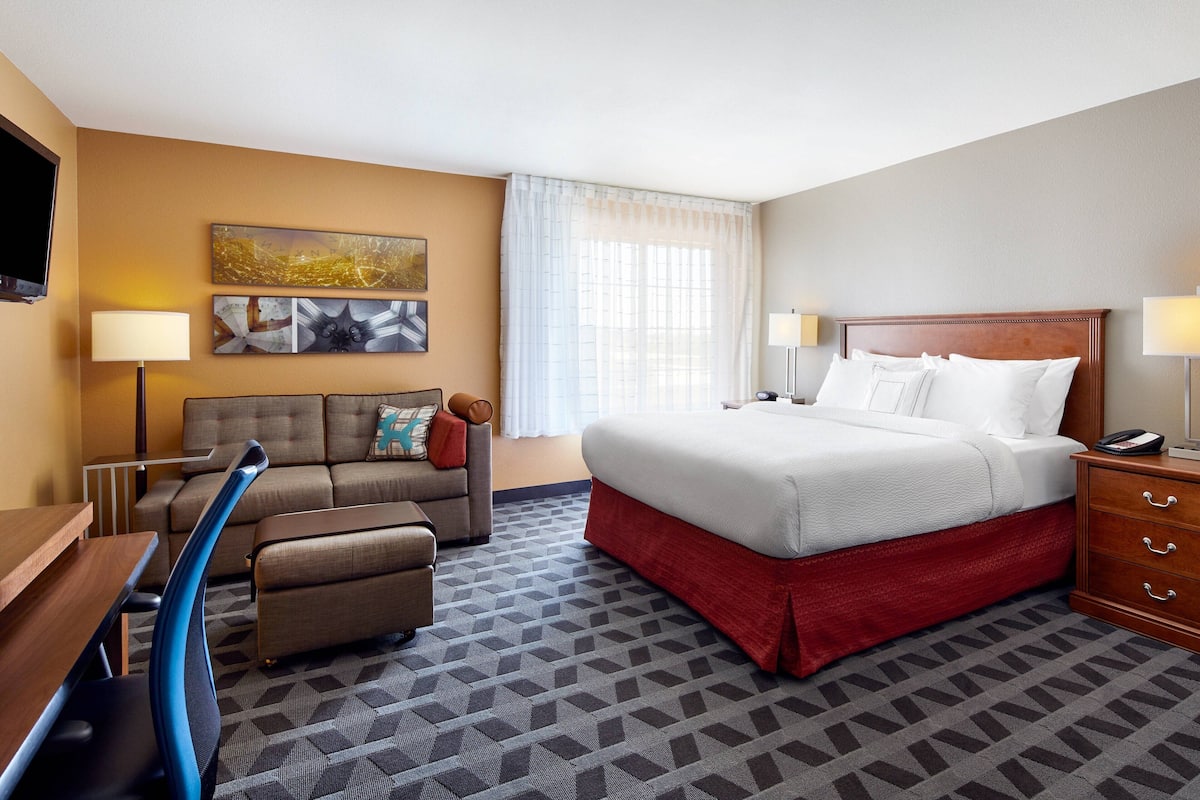 A hotel room with a bed, a sofa, a desk, and a TV.