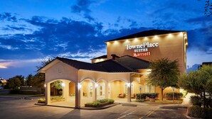 A hotel with a large sign reading "TownePlace Suites Marriott" and a covered entrance area with seating. - TownePlace Suites Midland (Midland)