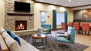 A spacious lobby with a stone fireplace, comfortable seating, and a dining area. - TownePlace Suites Midland (Midland)