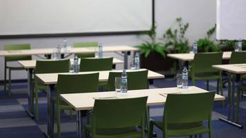Ett konferensrum med bord, stolar, vattenflaskor och en projektorduk.
