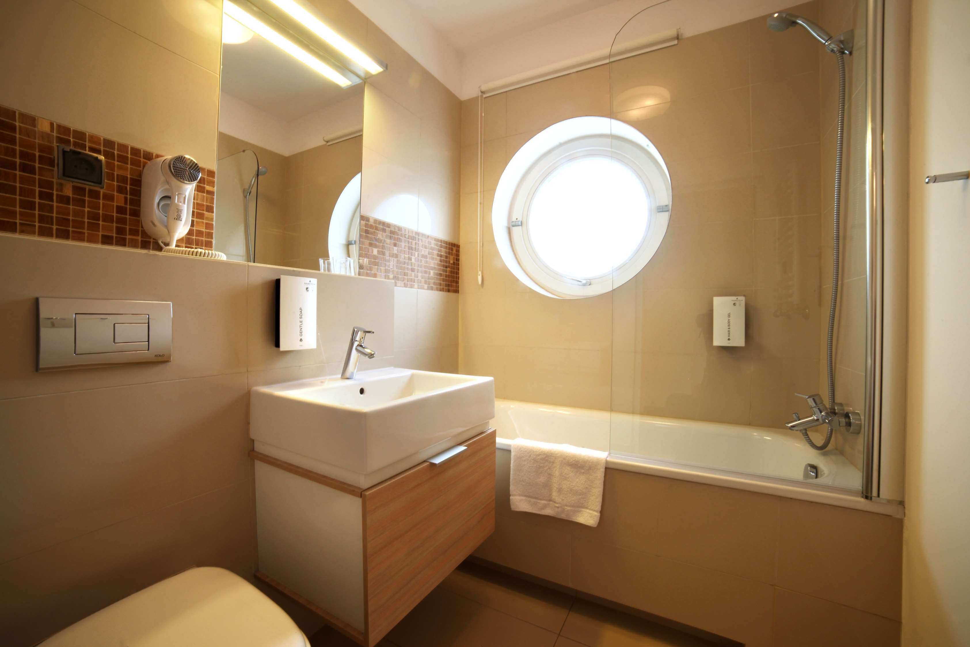 A bathroom with a sink, vanity, mirror, and a shower.