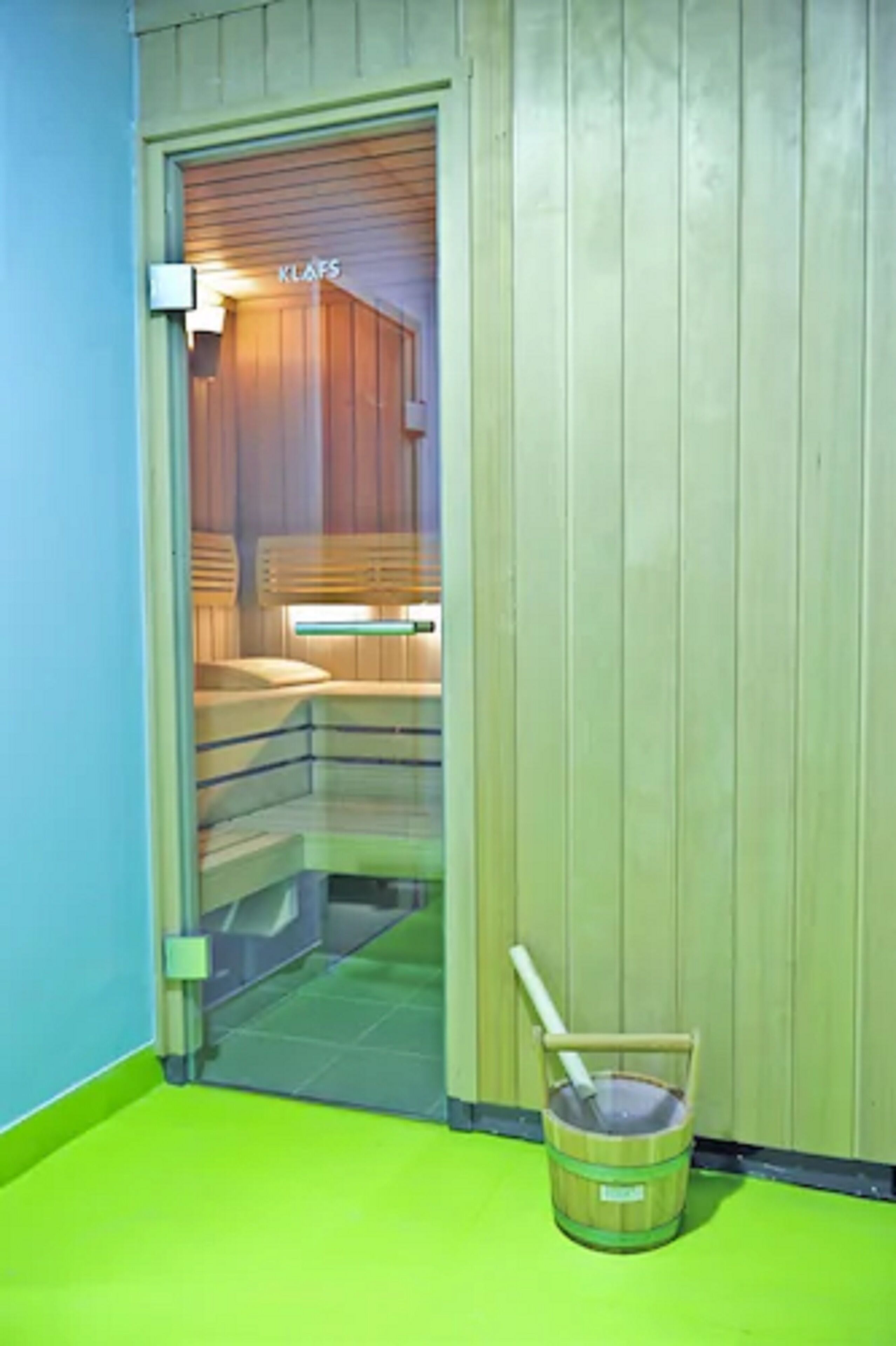 Un cuarto de sauna con bancos de madera y un letrero visible que dice "KLAFS".
