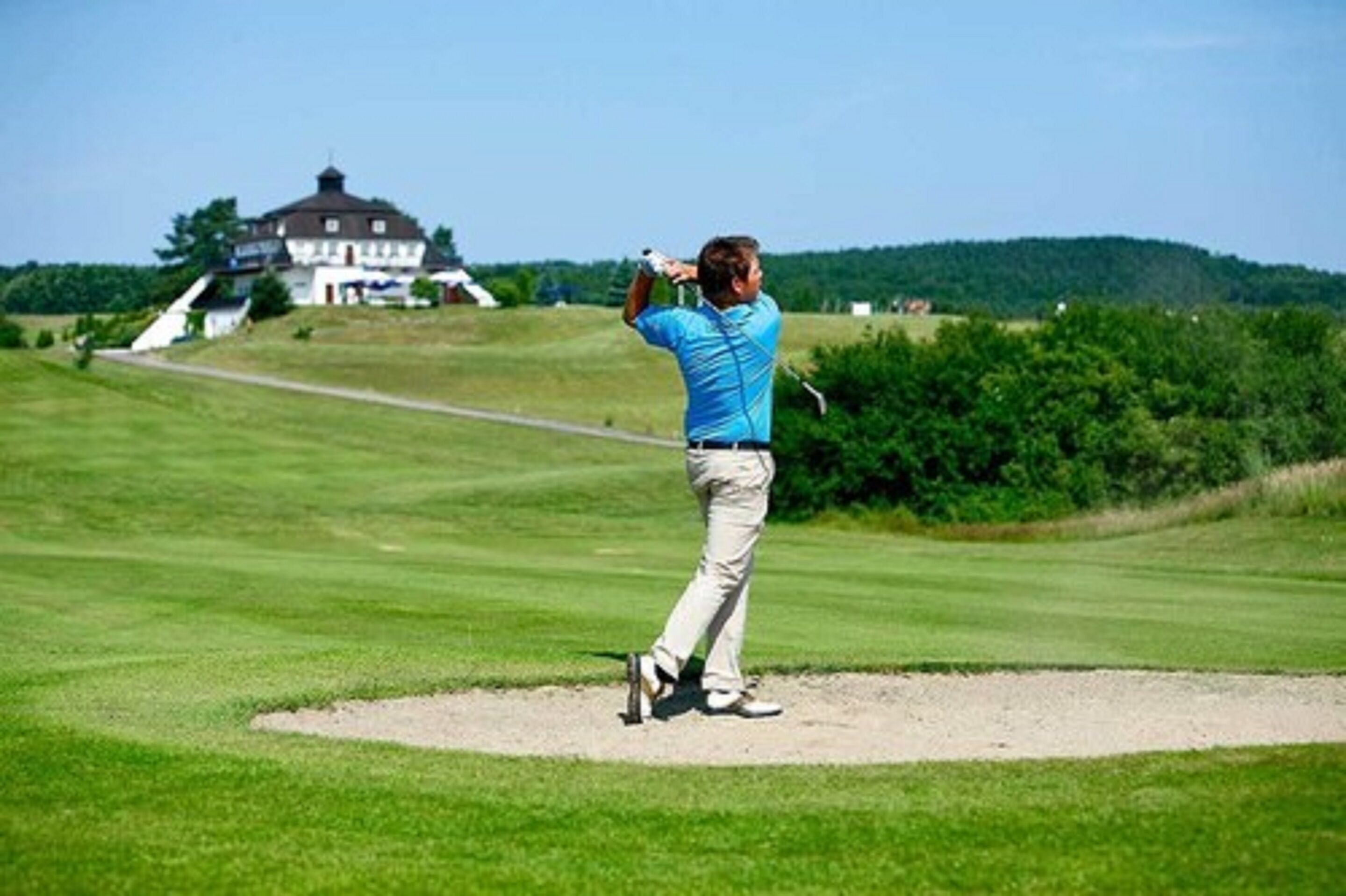 Ein Golfplatz mit einem Gebäude im Hintergrund.