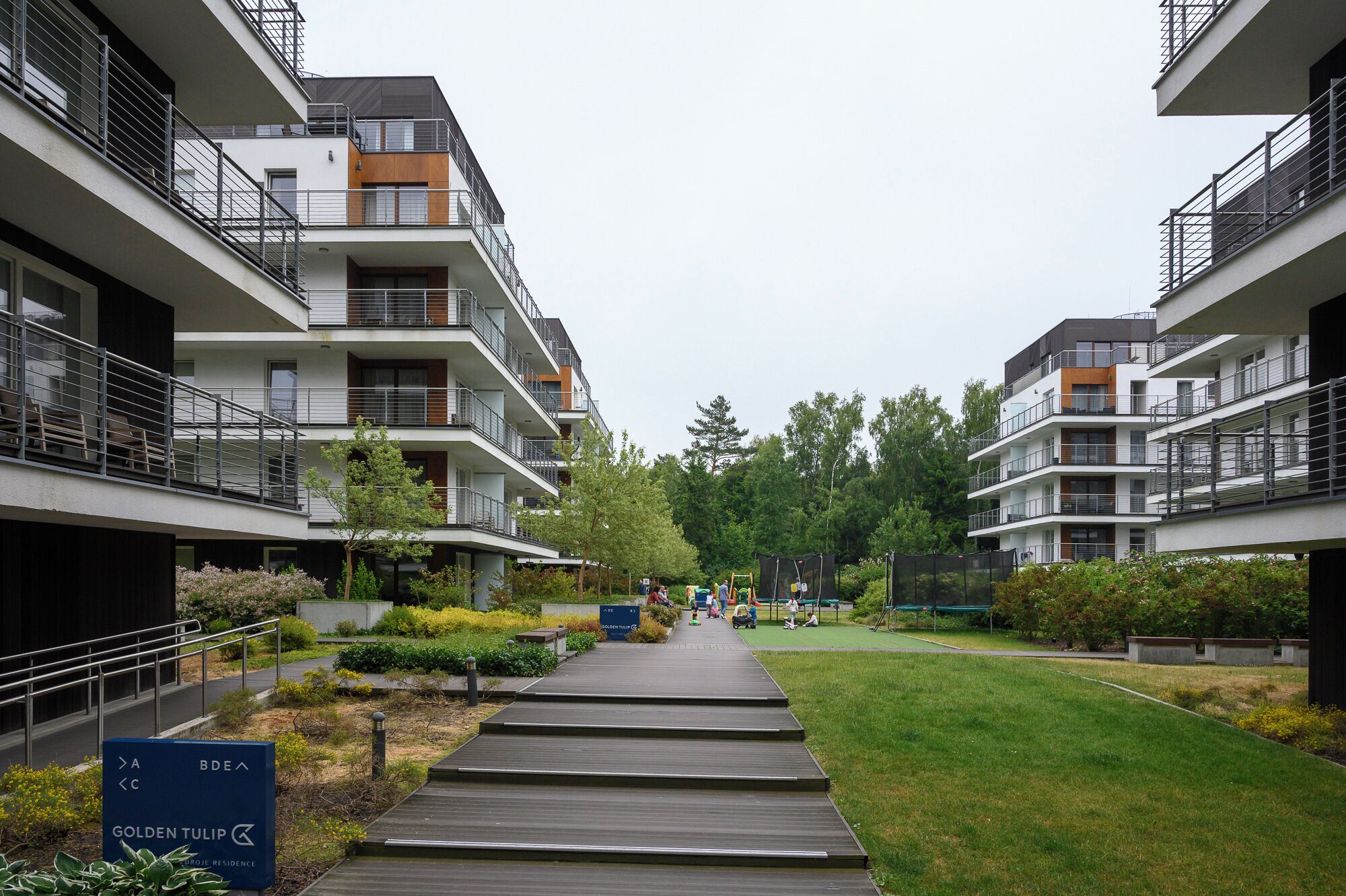 A modern residential building with multiple balconies, a central walkway, and a sign indicating 'Golden Tulip'.