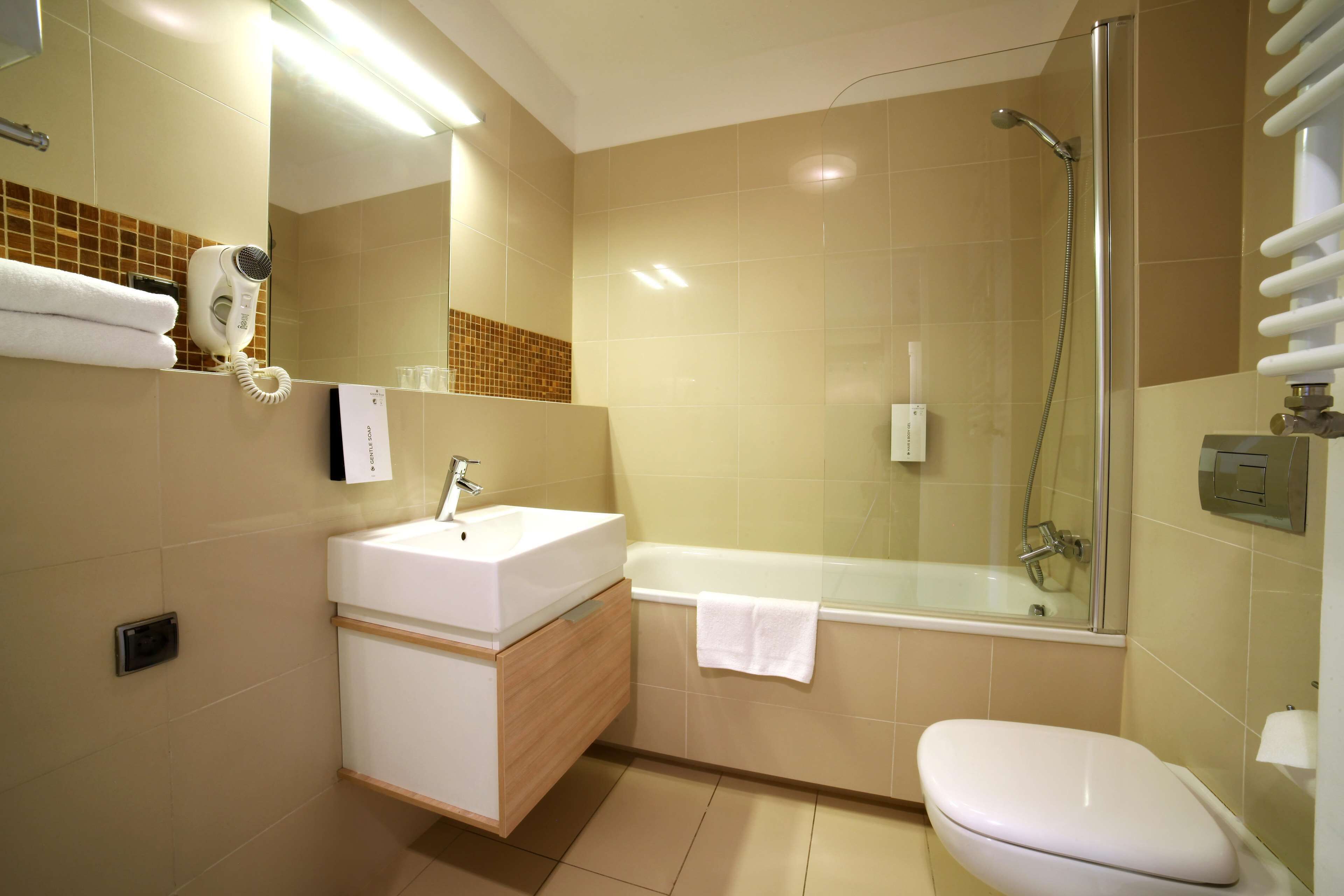 A bathroom with a sink, mirror, towel rack, and a glass-enclosed shower area.