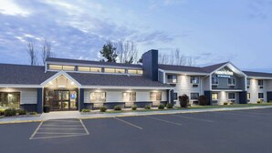 A hotel with a lobby entrance, multiple rooms, and a parking lot. - AmericInn by Wyndham Plover Stevens Point (Plover)