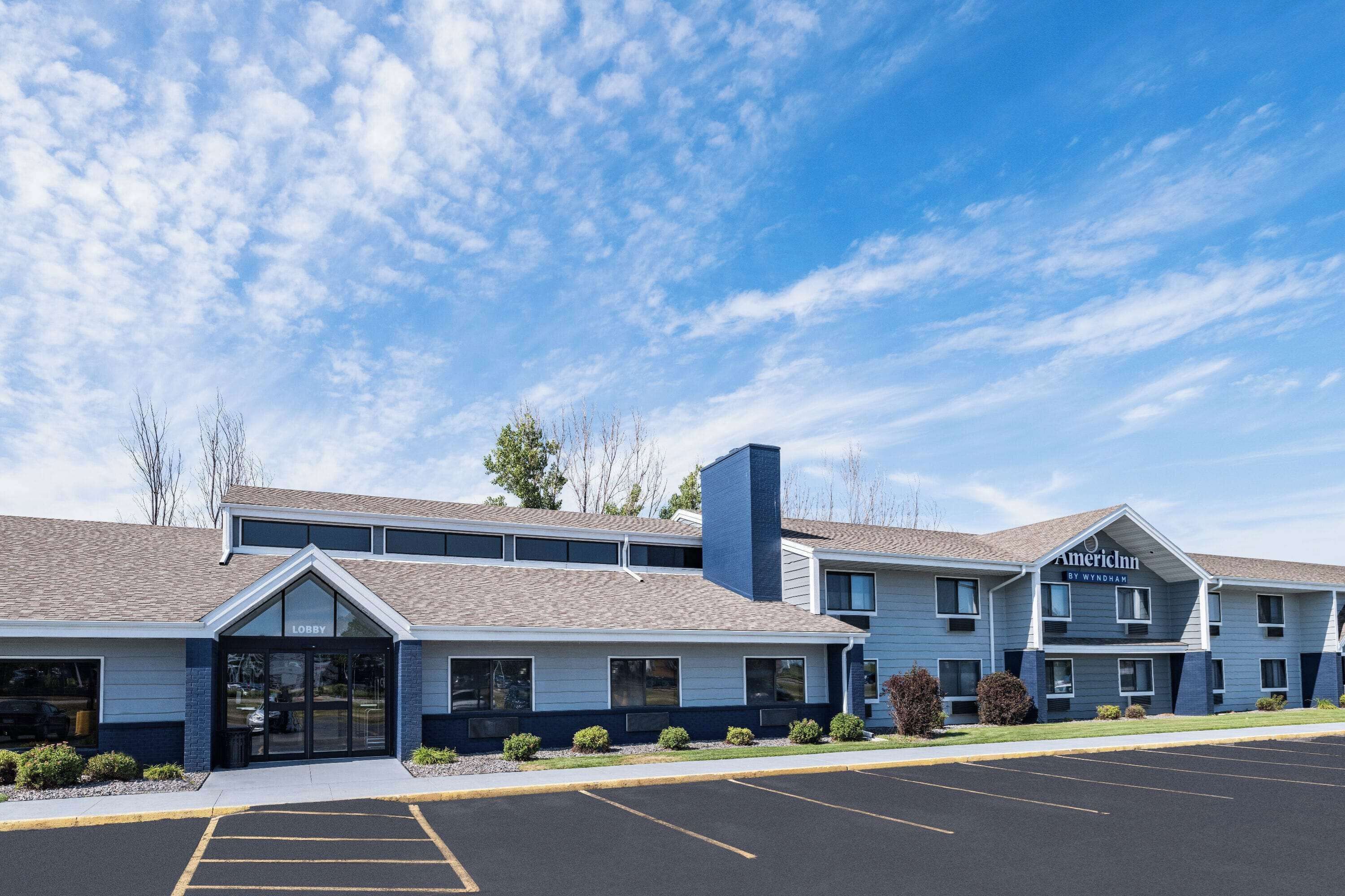 A two-story hotel with a 'Lobby' entrance, a parking lot, and a clear blue sky.