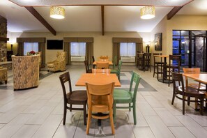 A dining area with multiple tables and chairs, a fireplace, and a television. - AmericInn by Wyndham Plover Stevens Point (Plover)