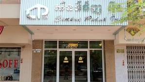 A hotel entrance with a sign in a foreign language, glass doors, and a red carpet. - Green Centre Point Inn (Phnom Penh)