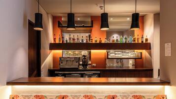 A bar area with a counter, hanging lights, and a patterned wall.