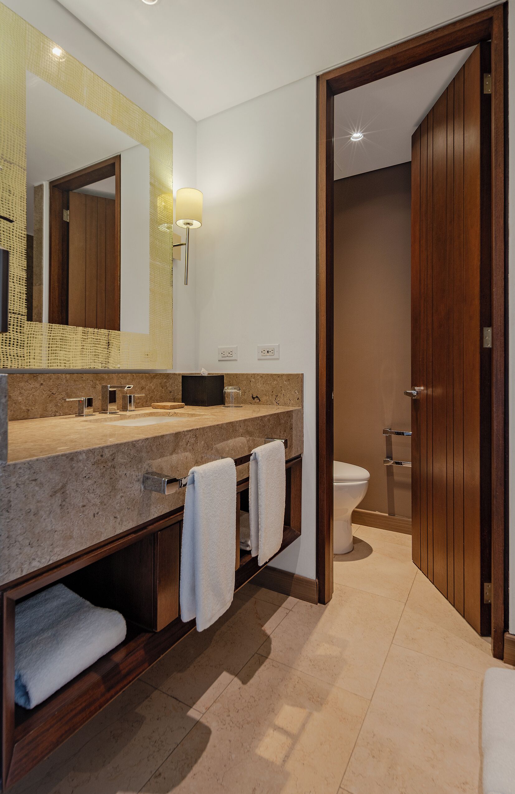 Un bagno moderno con uno specchio grande, un lavabo con porta asciugamani e un water.